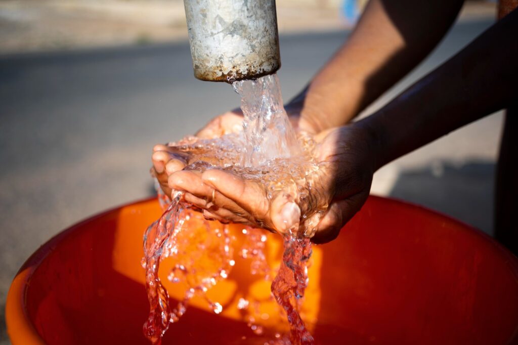 African woman pouring water in a recipient outdoors