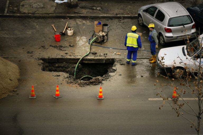 Construction workers draining a hole in the street